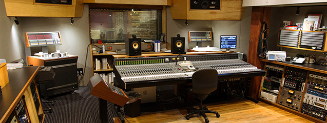 A control room at Electrical Audio — Neotek console with monitors, outboard racks, and a brick-walled live room visible through the window